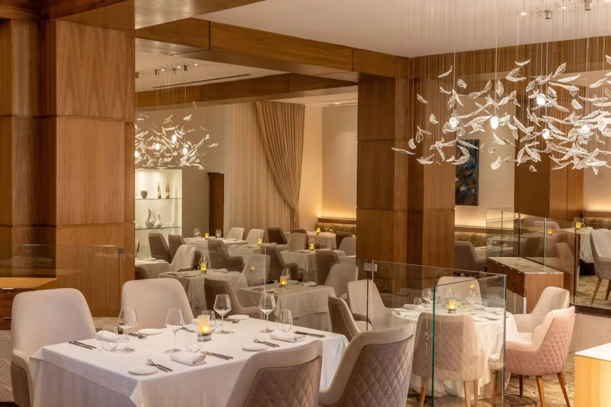 Bella Italian restaurant dining room with white-clothed tables and modern chandeliers at Le Blanc Spa Resort, Cancun
