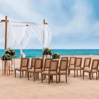 Beach wedding ceremony with white huppah and wooden chairs at Le Blanc Spa Resort, Cancun