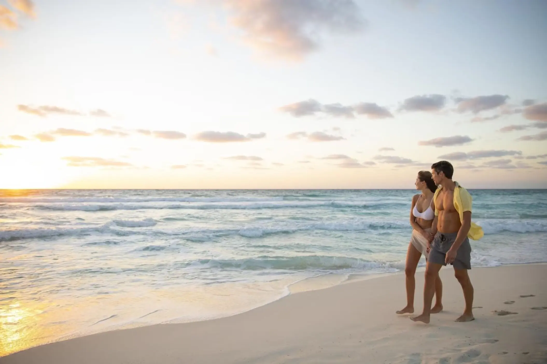 Couple walking along the shore at sunset at Le Blanc Spa Resort, Cancun