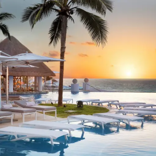 Infinity pool with submerged loungers at sunset, Le Blanc Spa Resort, Cancun