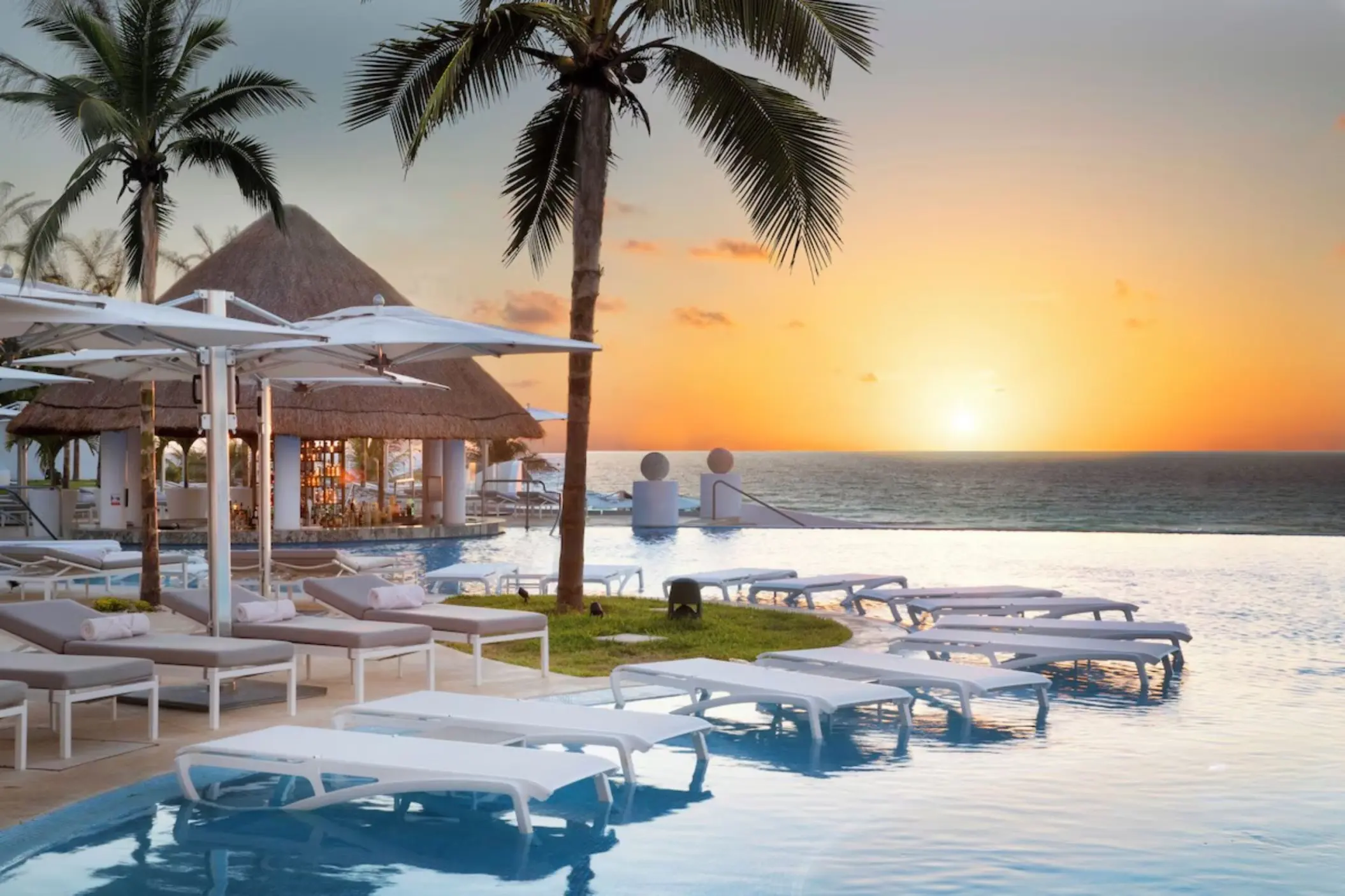 Infinity pool with submerged loungers at sunset, Le Blanc Spa Resort, Cancun