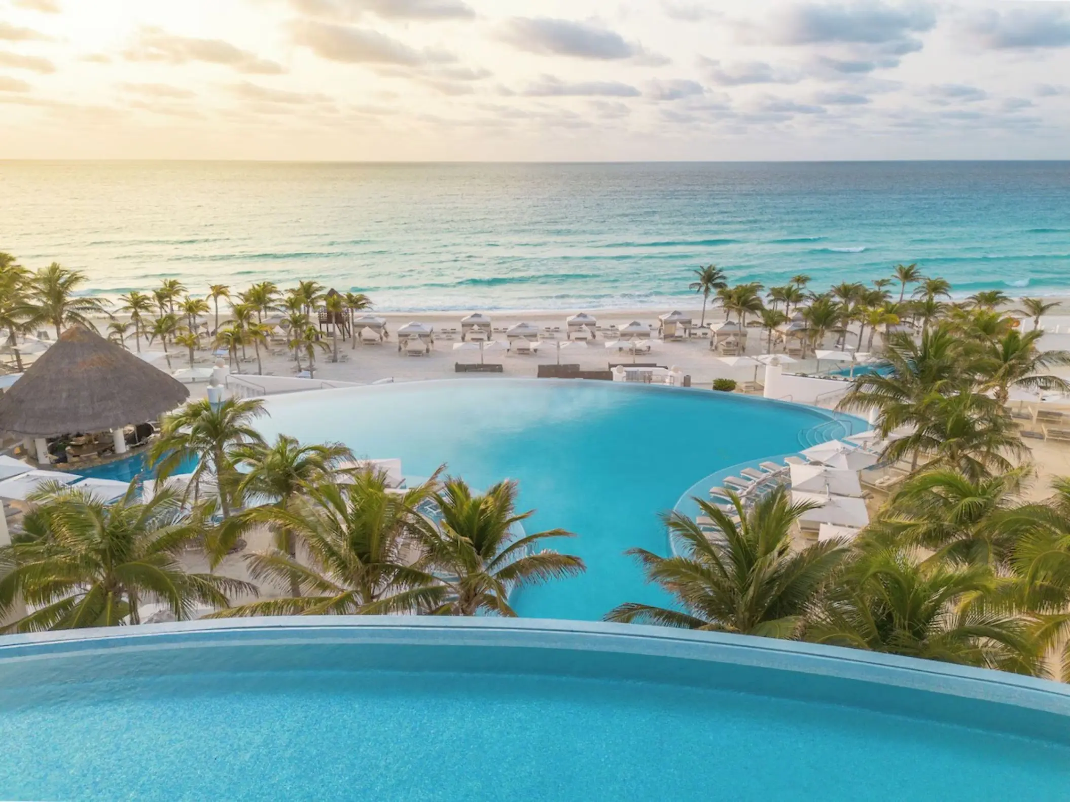 Tiered infinity pools overlooking the beach and turquoise ocean at Le Blanc Spa Resort, Cancun