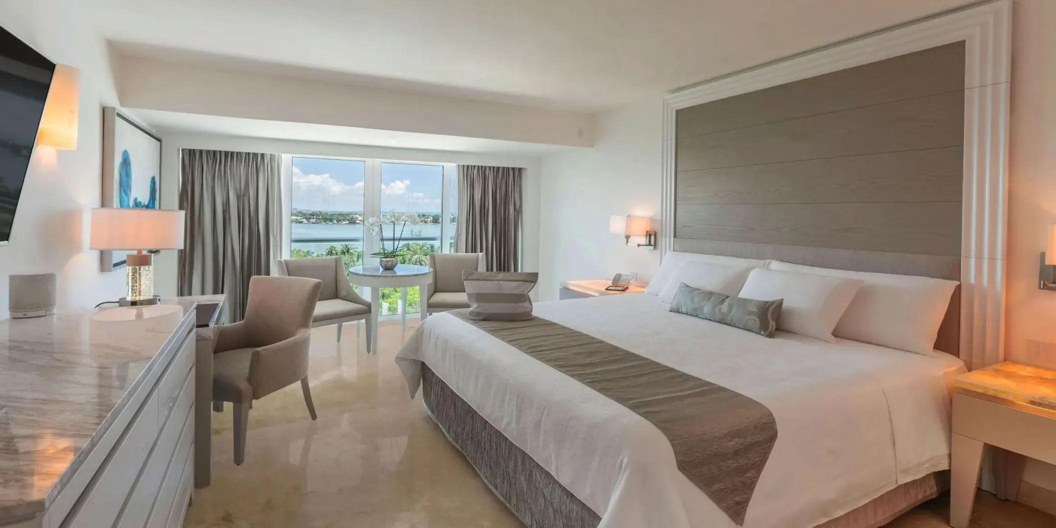 Royale Deluxe Lagoon View suite with white bedding and seating area at Le Blanc Spa Resort, Cancun