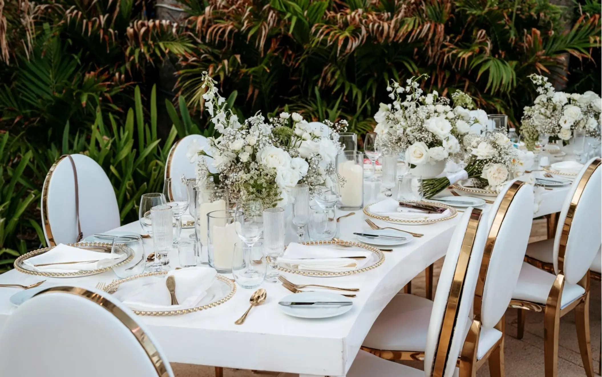 White and gold reception table with floral centerpieces at Live Aqua Cancun
