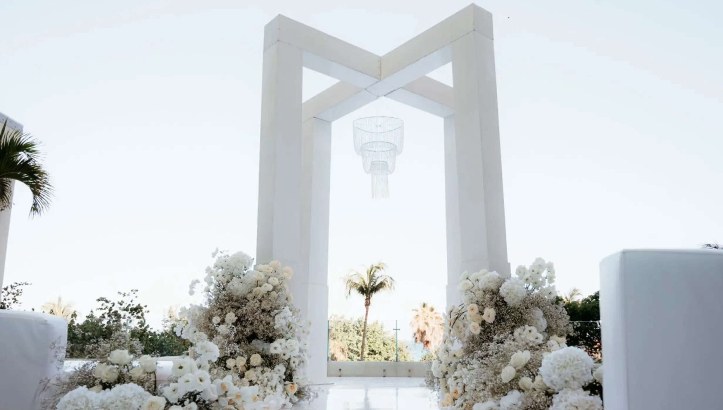 White Egos Terrace wedding ceremony with floral arrangements and modern arch at Live Aqua Cancun