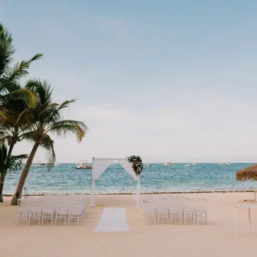 Beachfront wedding ceremony with a white fabric arch at Lopesan Costa Bavaro, Punta Cana