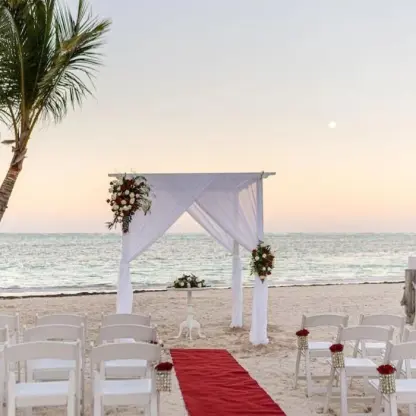 Beachfront wedding ceremony with white draped arch and red aisle runner at Lopesan Costa Bavaro, Punta Cana