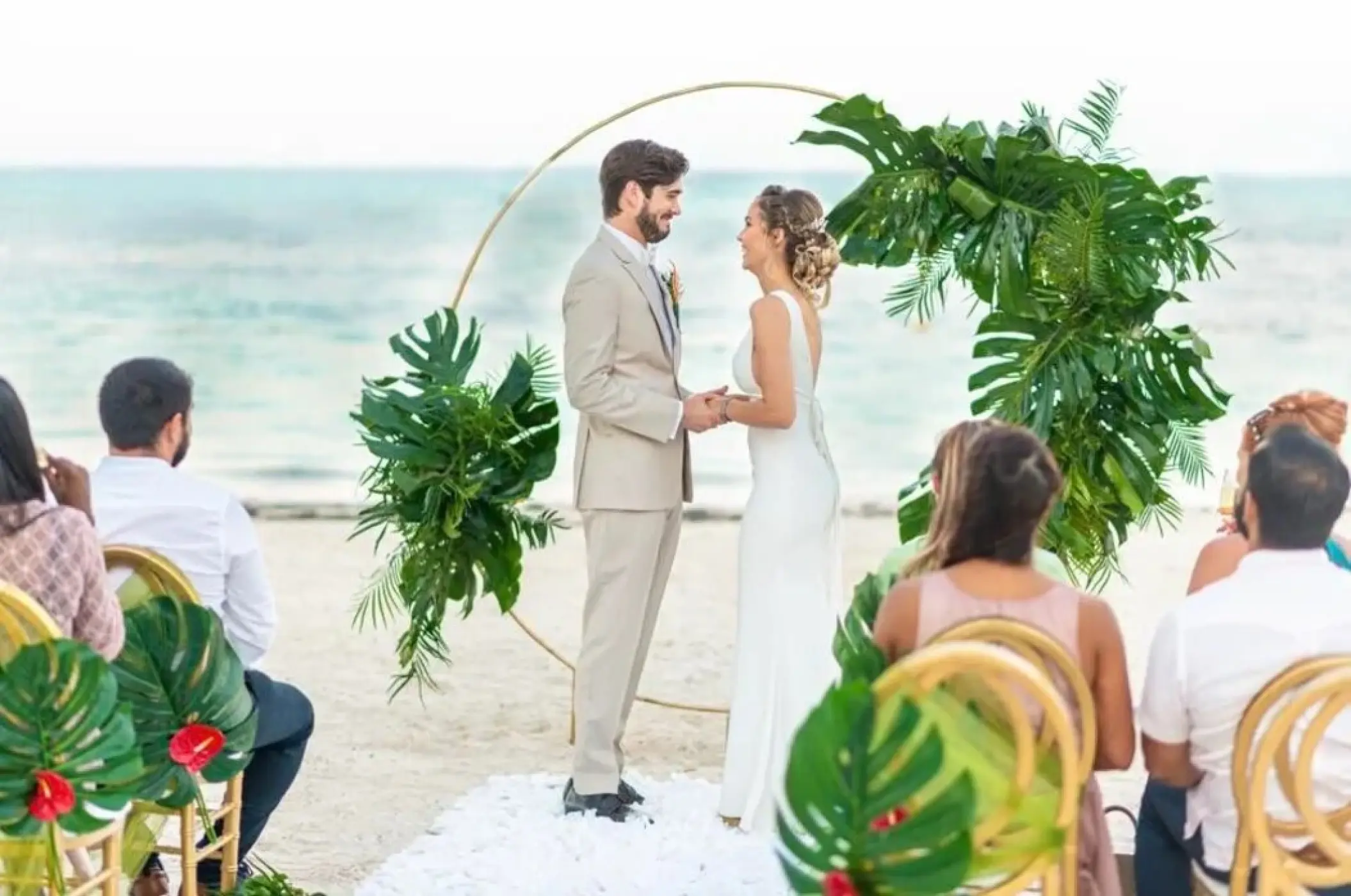 Beachfront wedding ceremony with a tropical leaf arch at Lopesan Costa Bavaro, Punta Cana