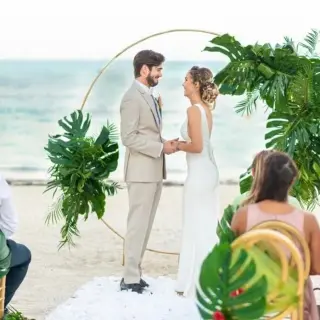 Beachfront wedding ceremony with a tropical leaf arch at Lopesan Costa Bavaro, Punta Cana