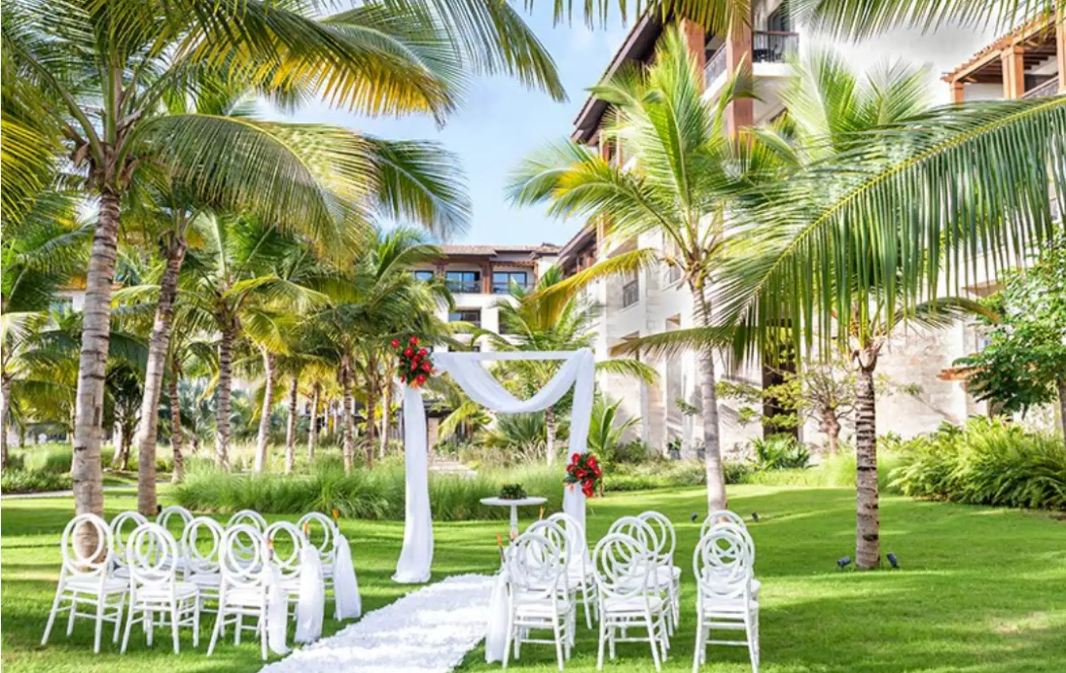 Garden wedding ceremony setup with white chairs and floral arch at Lopesan Costa Bavaro, Punta Cana