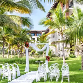Garden wedding ceremony setup with white chairs and floral arch at Lopesan Costa Bavaro, Punta Cana