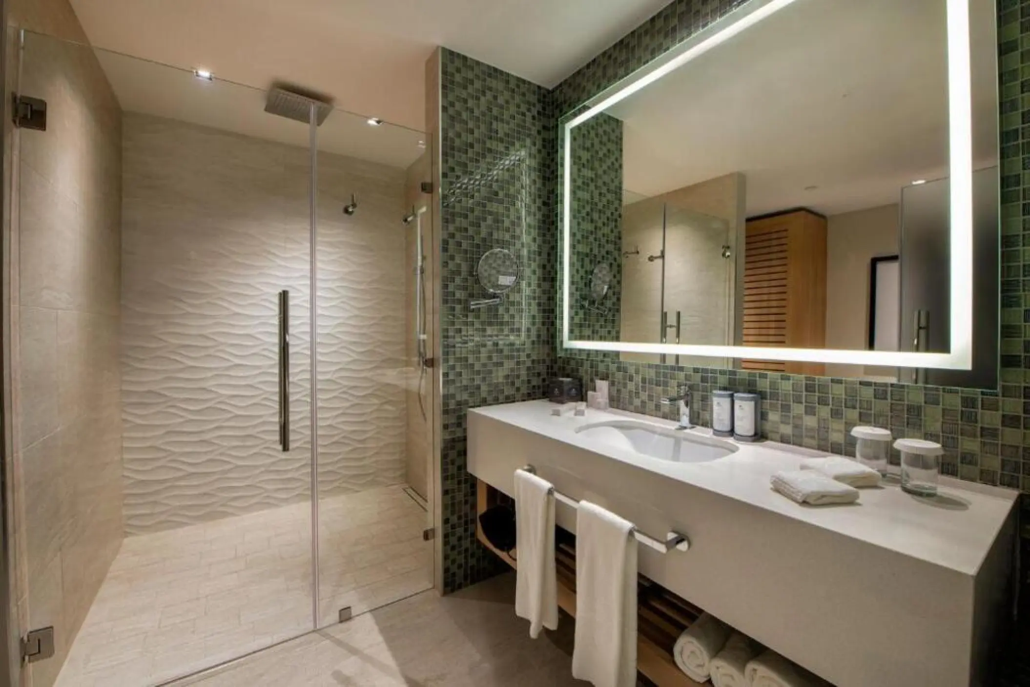Modern suite bathroom with green mosaic tiles and walk-in shower at Lopesan Costa Bavaro, Punta Cana