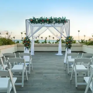 Rooftop wedding ceremony with white chairs and floral huppah at Lopesan Costa Bavaro, Punta Cana