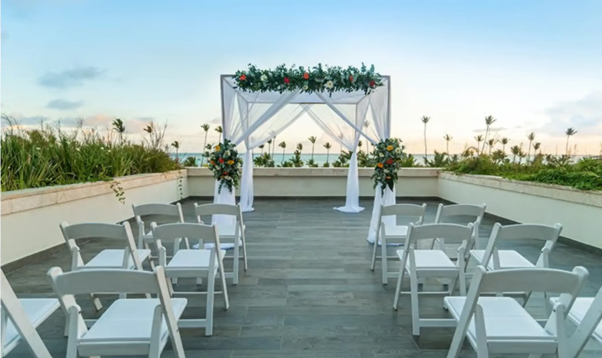 Rooftop wedding ceremony with white chairs and floral huppah at Lopesan Costa Bavaro, Punta Cana