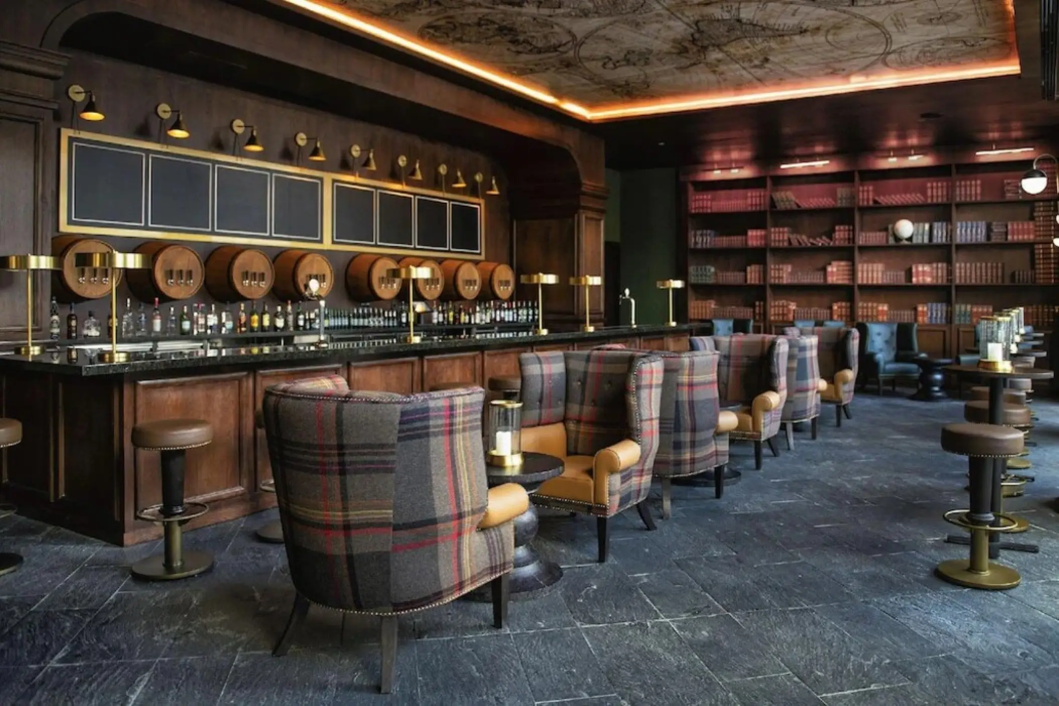 Wine bar with plaid armchairs and book-lined walls at Lopesan Costa Bavaro, Punta Cana