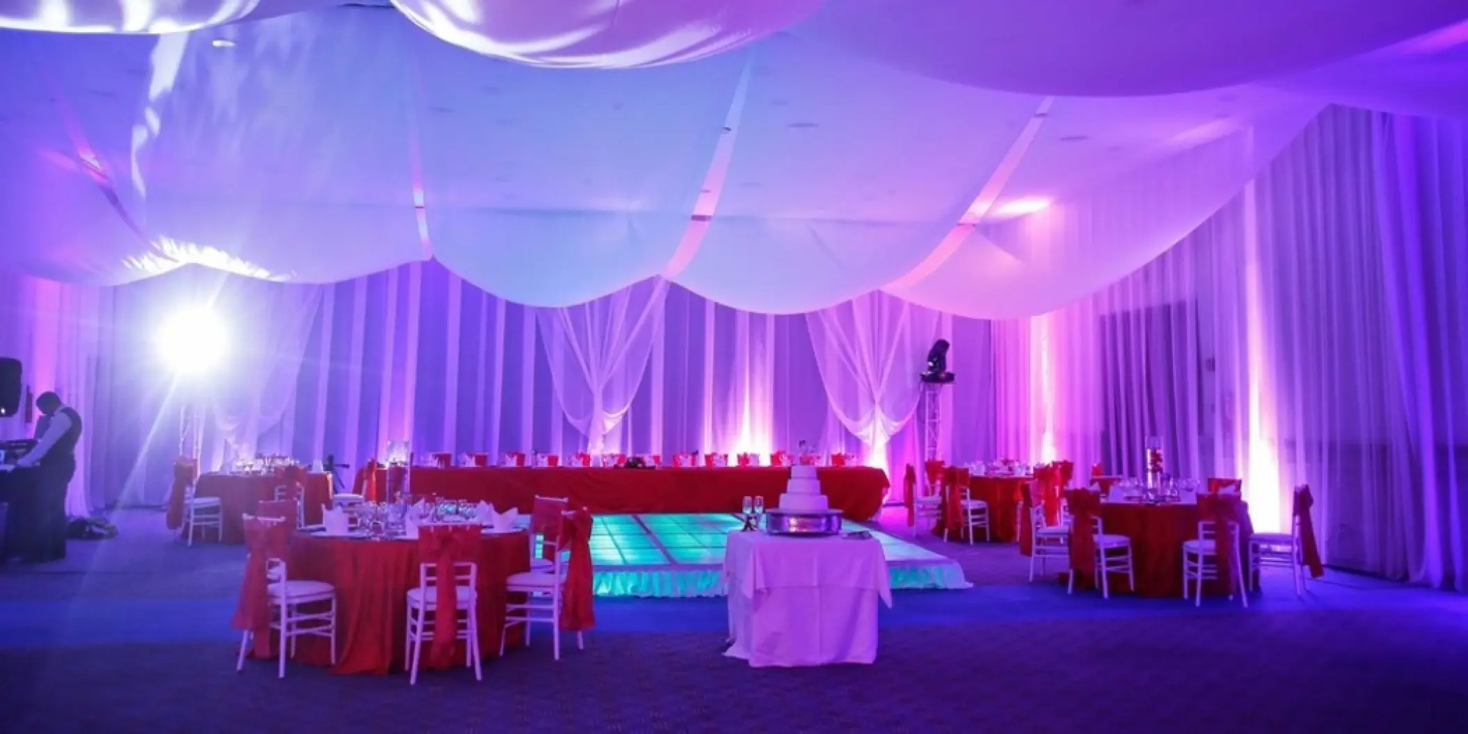 Indoor wedding reception with purple lighting and red table linens at Majestic Colonial, Punta Cana