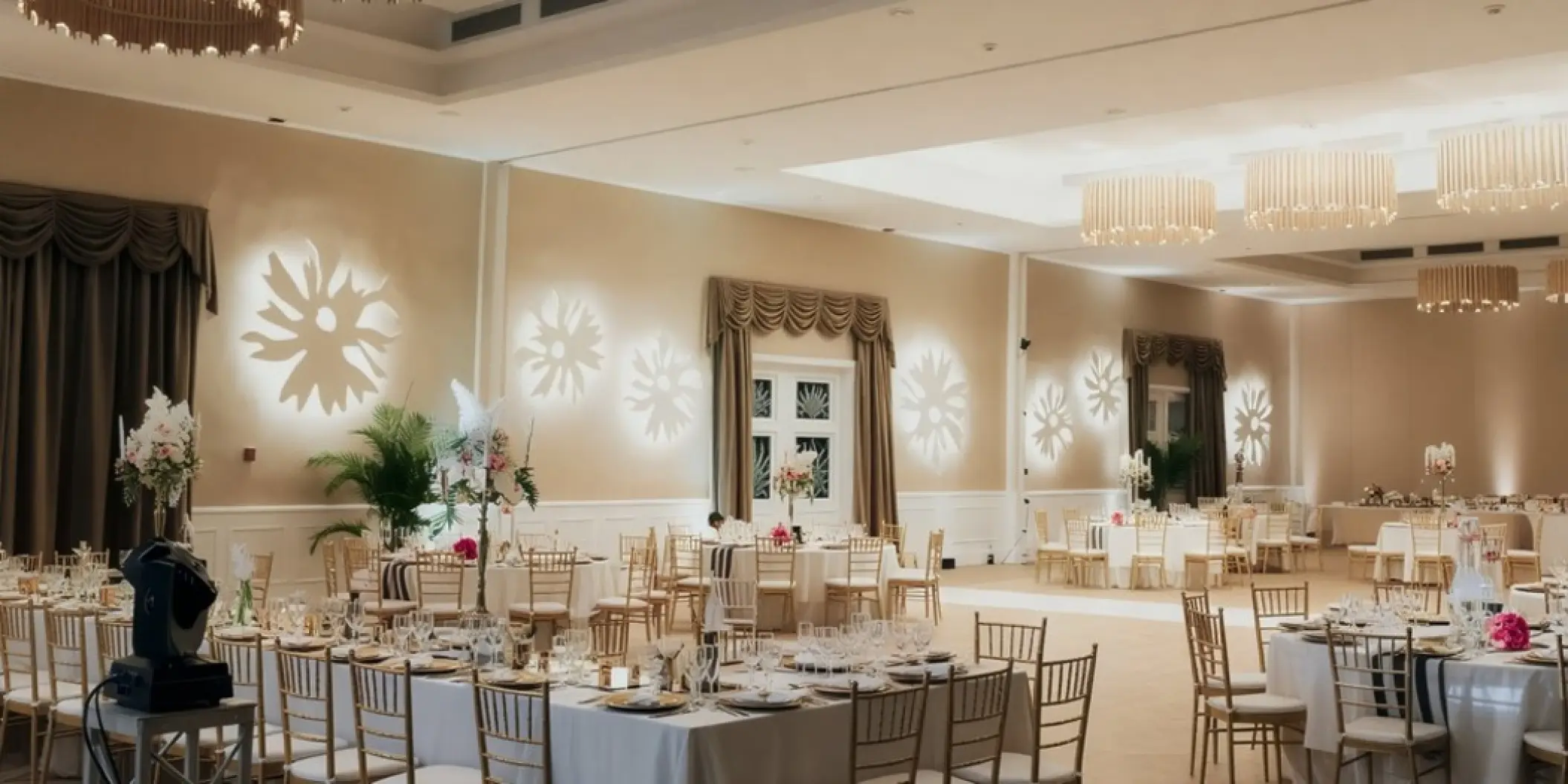 Ballroom wedding reception with flower light projections and gold chairs at Majestic Colonial, Punta Cana