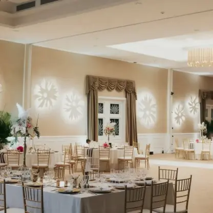 Ballroom wedding reception with flower light projections and gold chairs at Majestic Colonial, Punta Cana