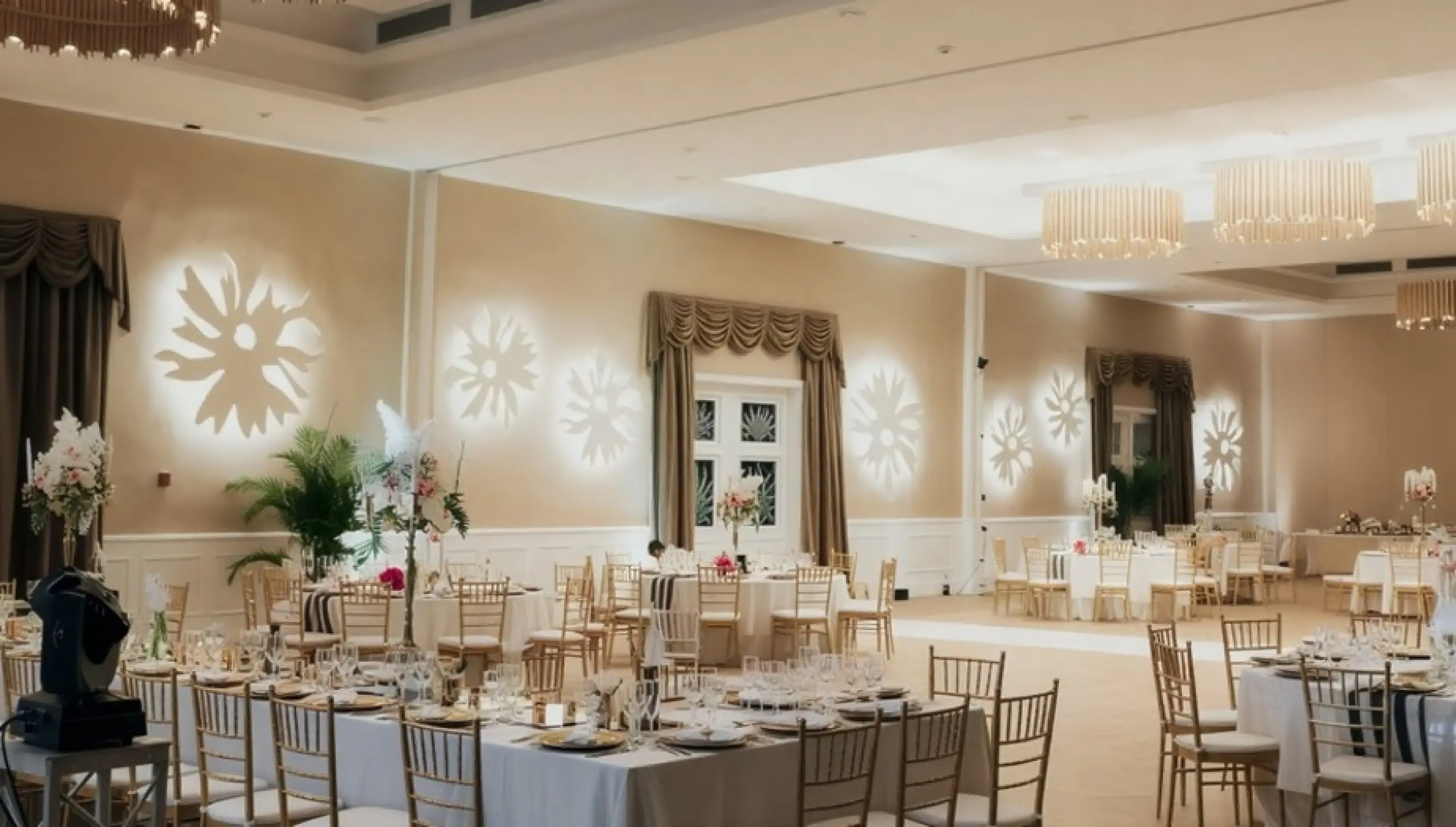 Ballroom wedding reception with flower light projections and gold chairs at Majestic Colonial, Punta Cana