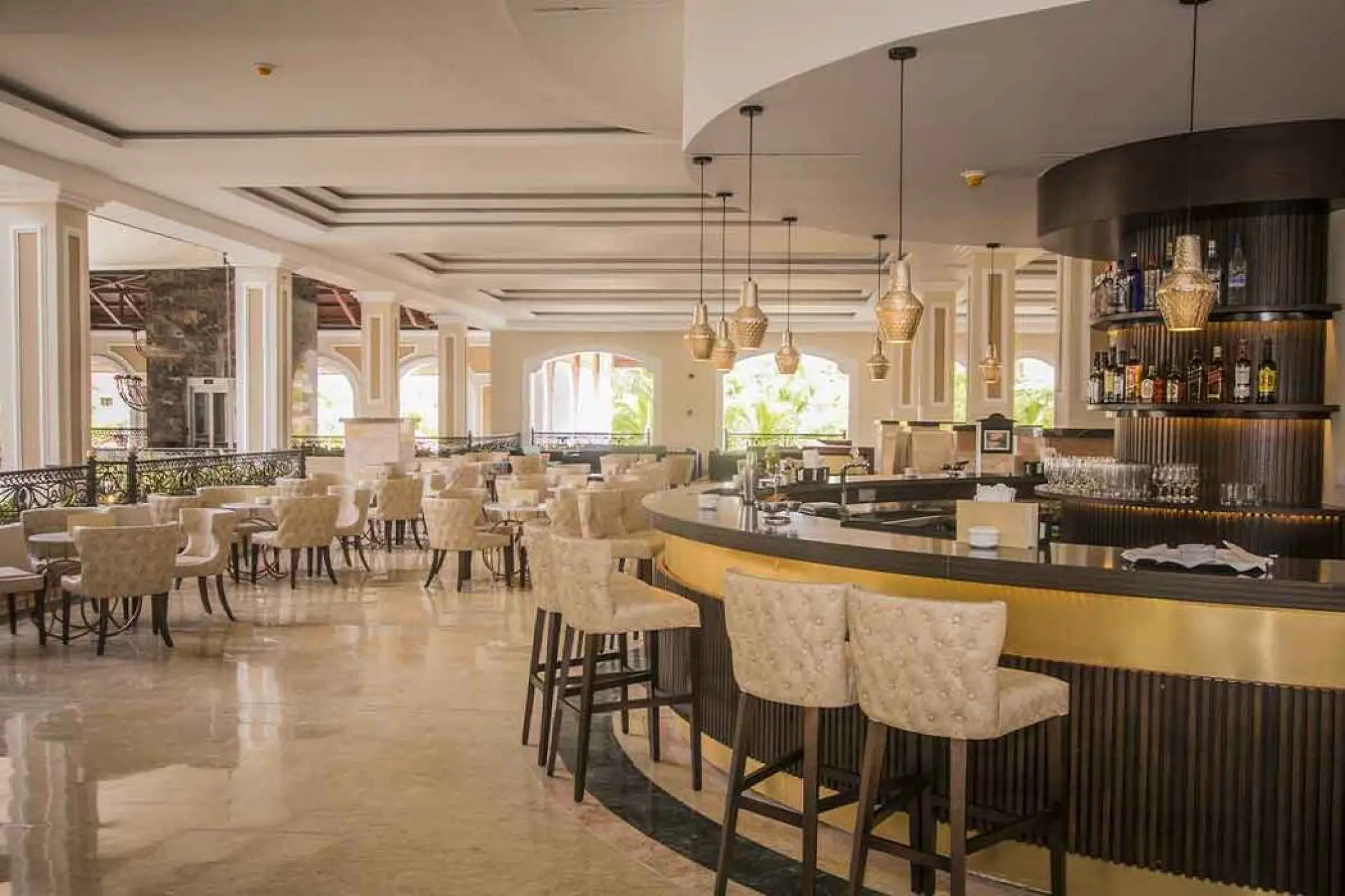 Indoor lobby bar with tufted chairs and hanging gold lamps at Majestic Colonial, Punta Cana