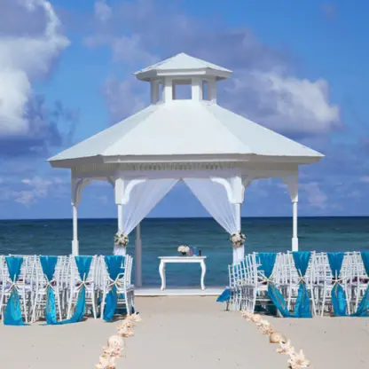 Beach gazebo wedding ceremony with white chairs and teal sashes at Majestic Colonial, Punta Cana