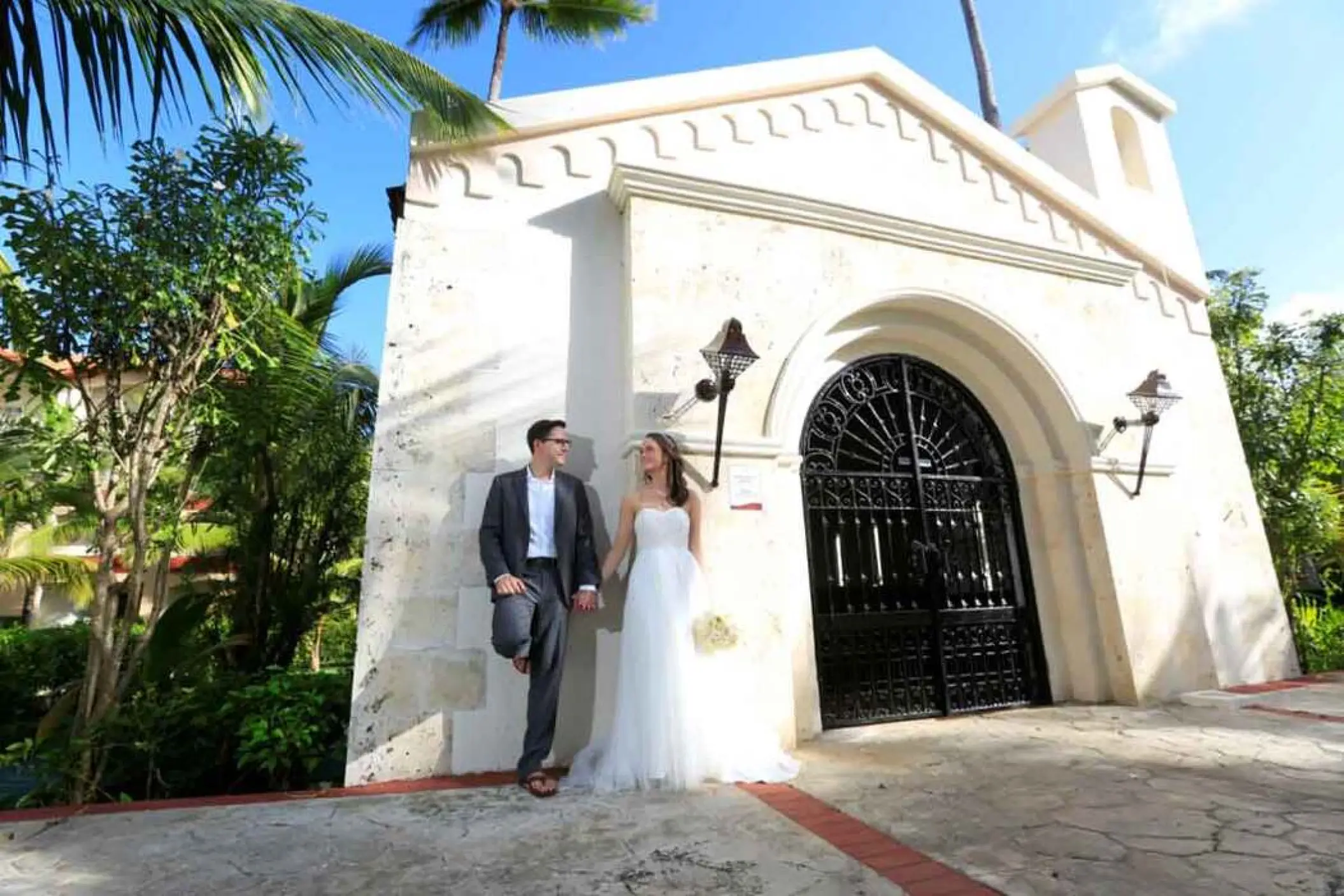 Bride and groom posing by the stone chapel at Majestic Colonial, Punta Cana