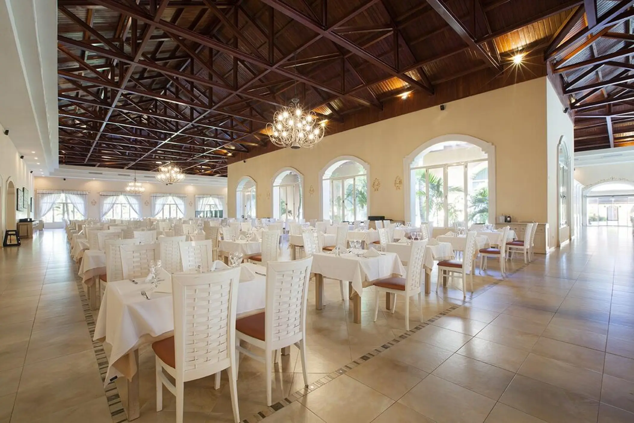 Indoor restaurant with vaulted wooden ceilings and white linens at Majestic Colonial, Punta Cana