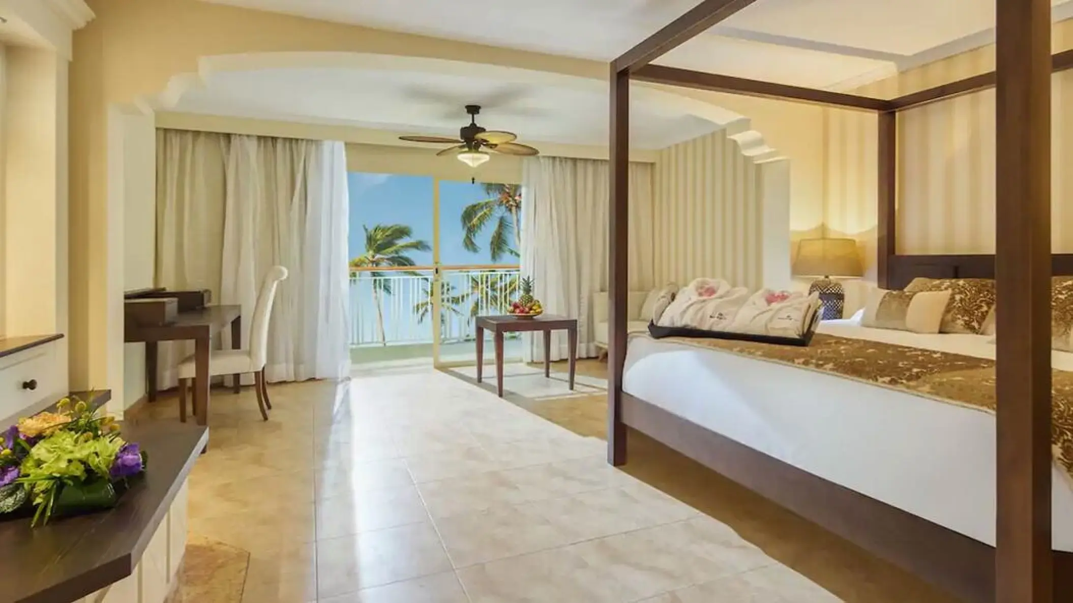 Suite with a four-poster bed and ocean view balcony at Majestic Colonial, Punta Cana