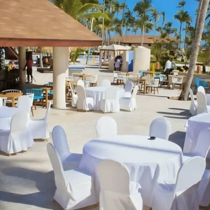 Outdoor wedding reception setup with white linen tables next to the pool bar at Majestic Colonial, Punta Cana