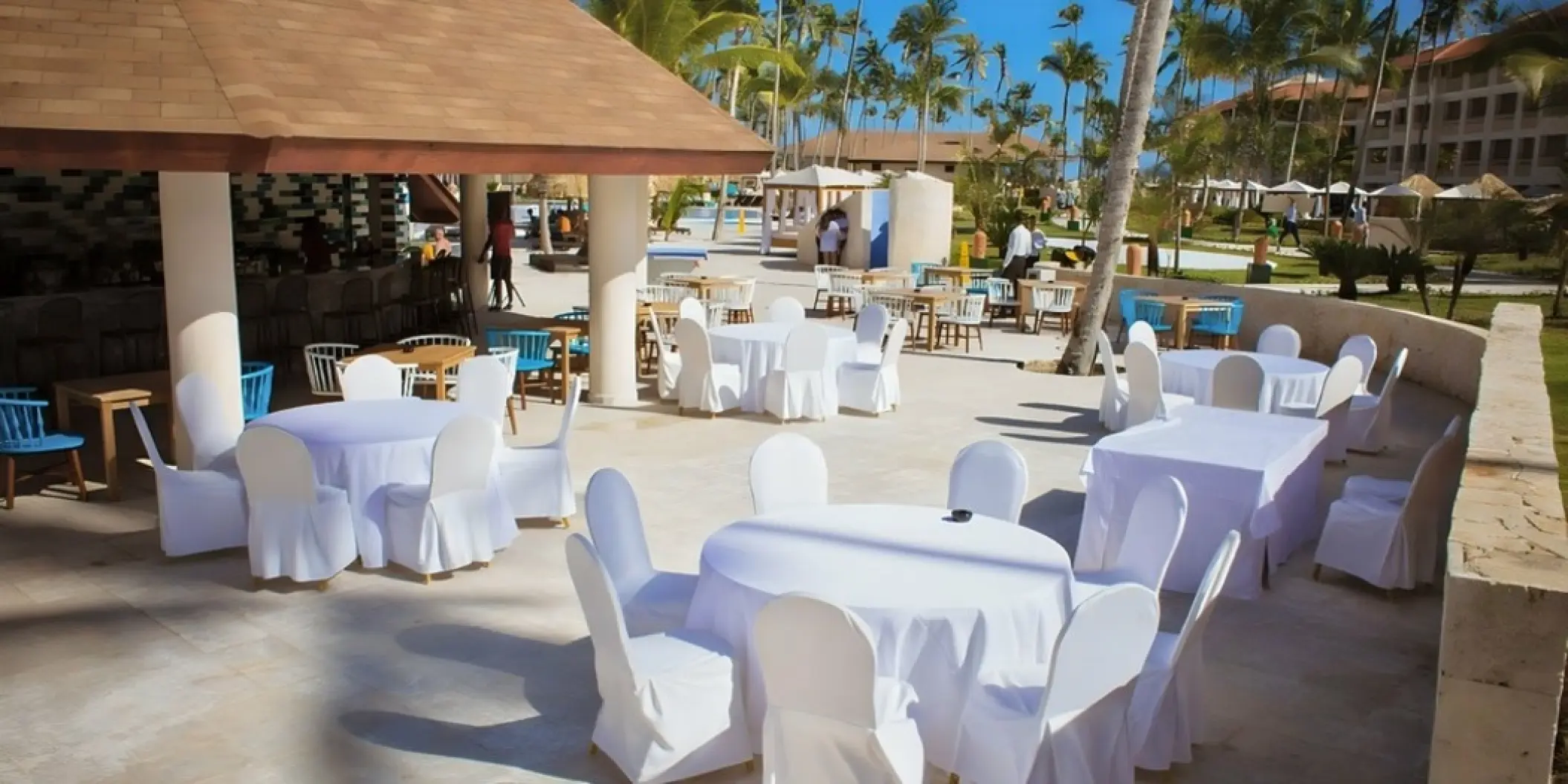 Outdoor wedding reception setup with white linen tables next to the pool bar at Majestic Colonial, Punta Cana