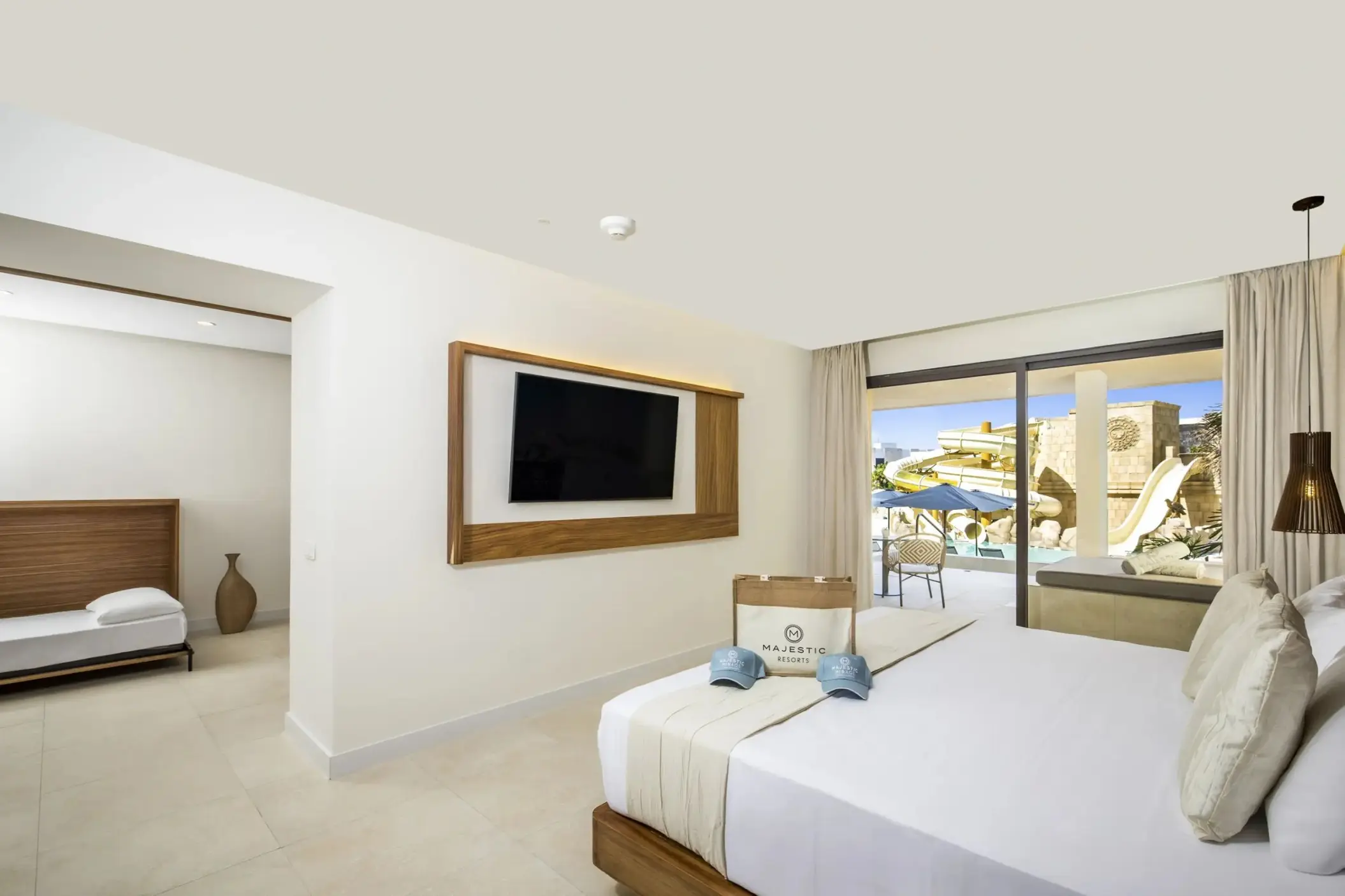 Modern suite interior with white linens and pool view balcony at Majestic Mirage Costa Mujeres, Cancun