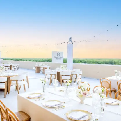 Rooftop wedding reception with white floral centerpieces and string lights at Majestic Mirage, Cancun