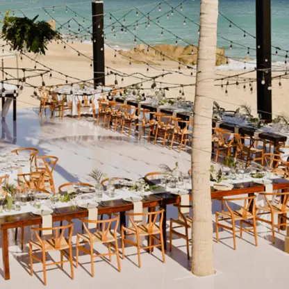 Beachfront wedding reception setup with string lights and wooden chairs at Mar Del Cabo, Cabo San Lucas