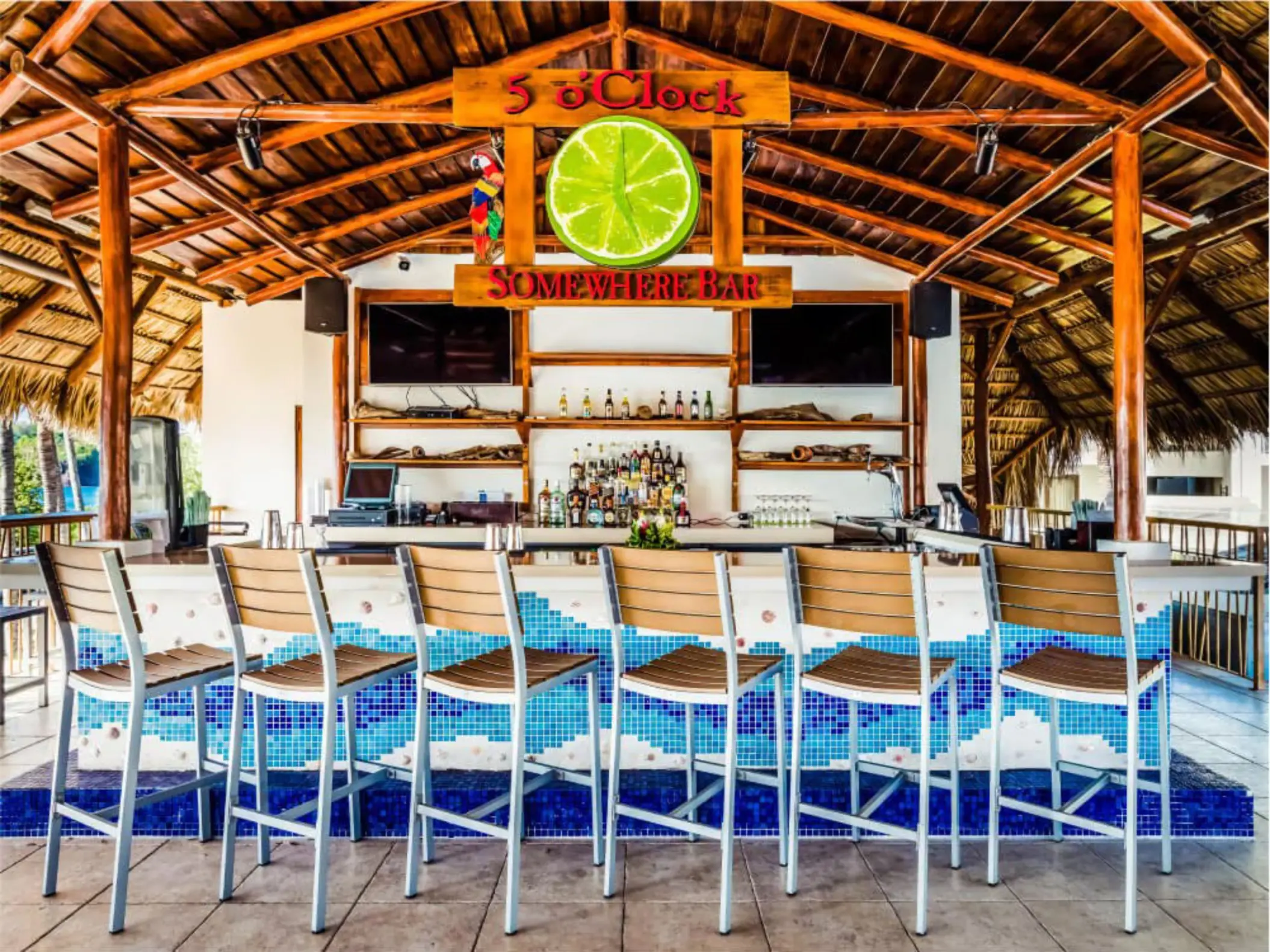 5 o'Clock Somewhere Bar with blue mosaic tile and wooden stools at Margaritaville Playa Flamingo, Liberia