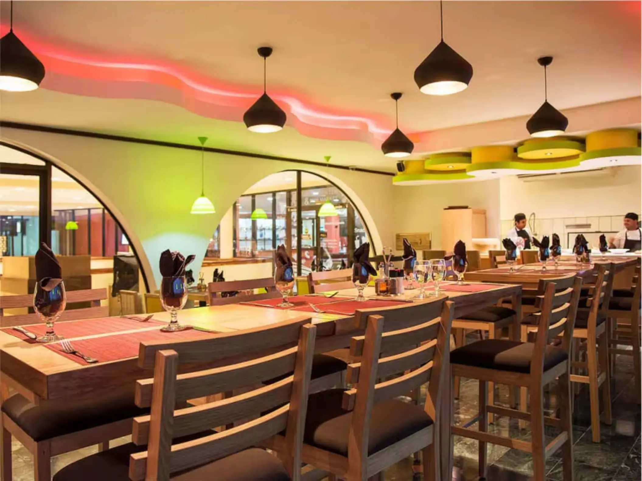 Modern indoor dining room with pendant lighting and long wooden tables at Margaritaville Playa Flamingo, Liberia