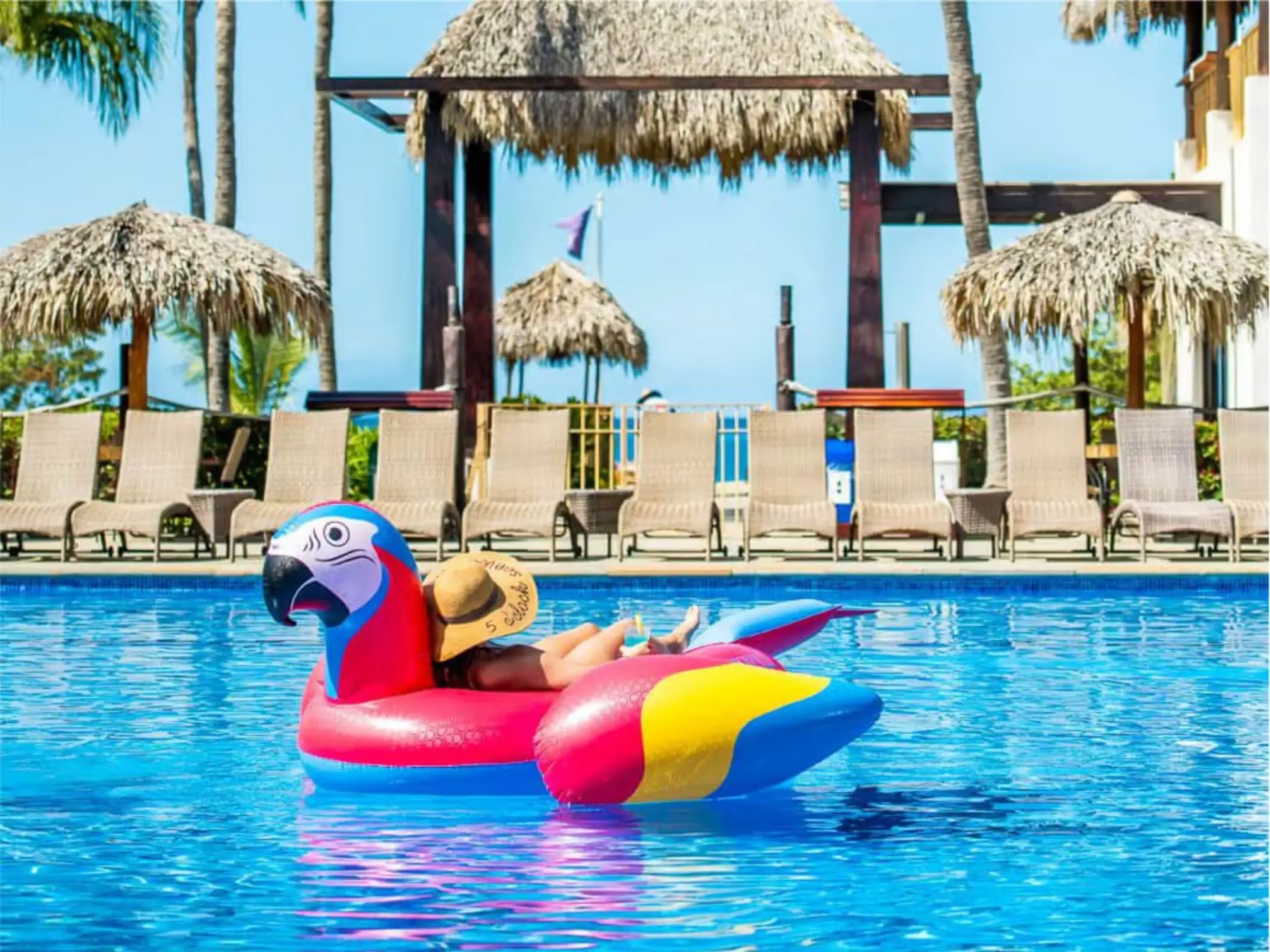Guest lounging on a parrot pool float at Margaritaville Beach Resort Playa Flamingo, Liberia