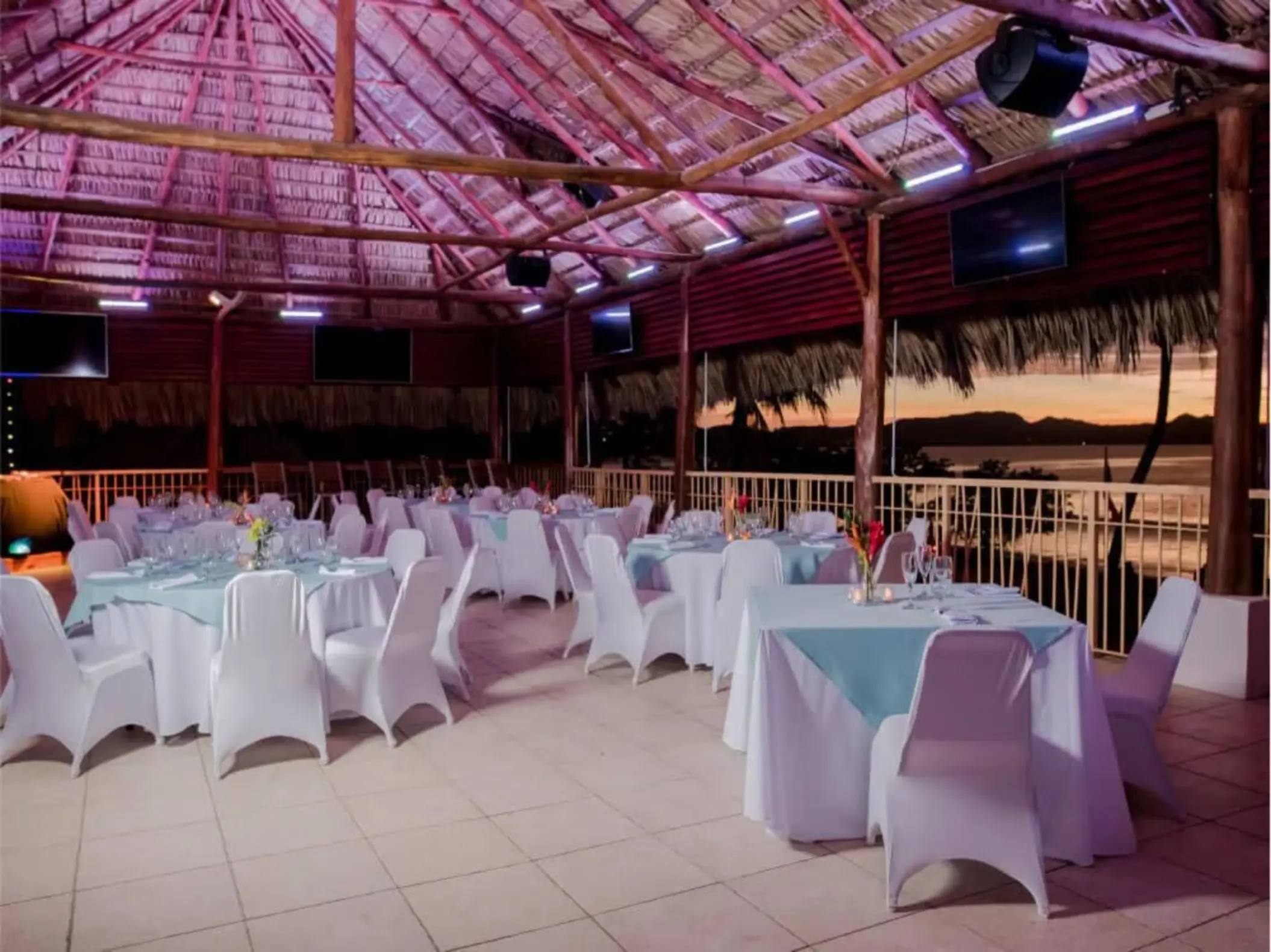Wedding reception setup under a thatched palapa at Margaritaville Playa Flamingo, Liberia