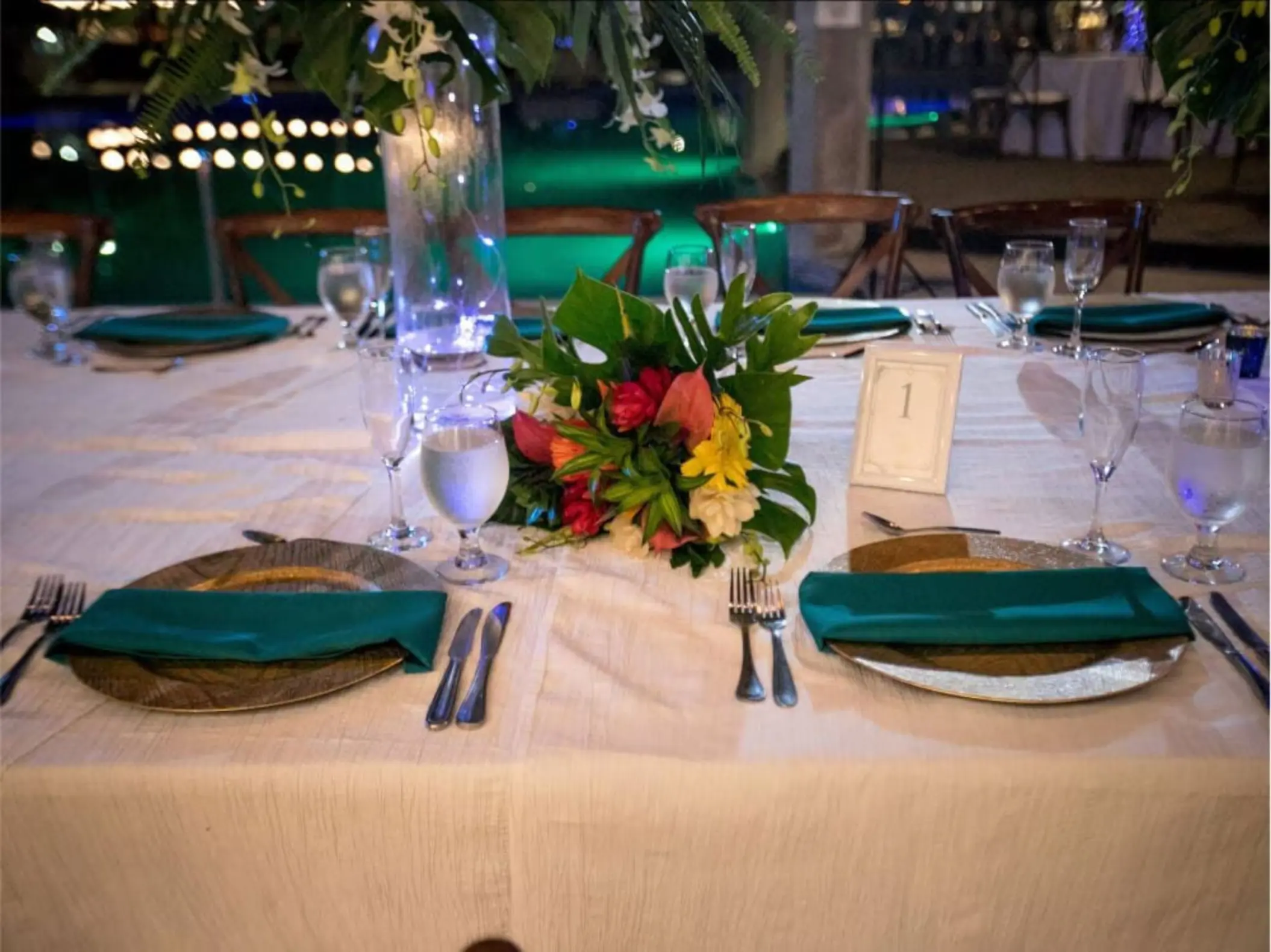Wedding reception table setup with tropical flowers and green napkins at Margaritaville Playa Flamingo, Liberia