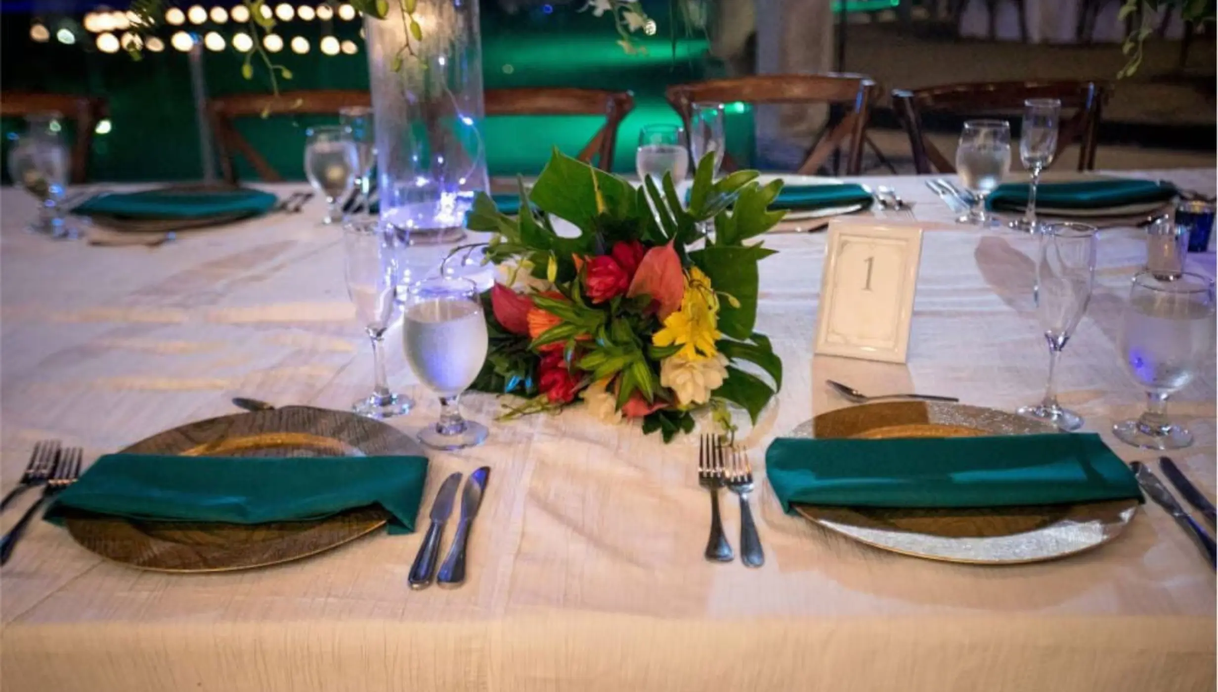 Wedding reception table setup with tropical flowers and green napkins at Margaritaville Playa Flamingo, Liberia