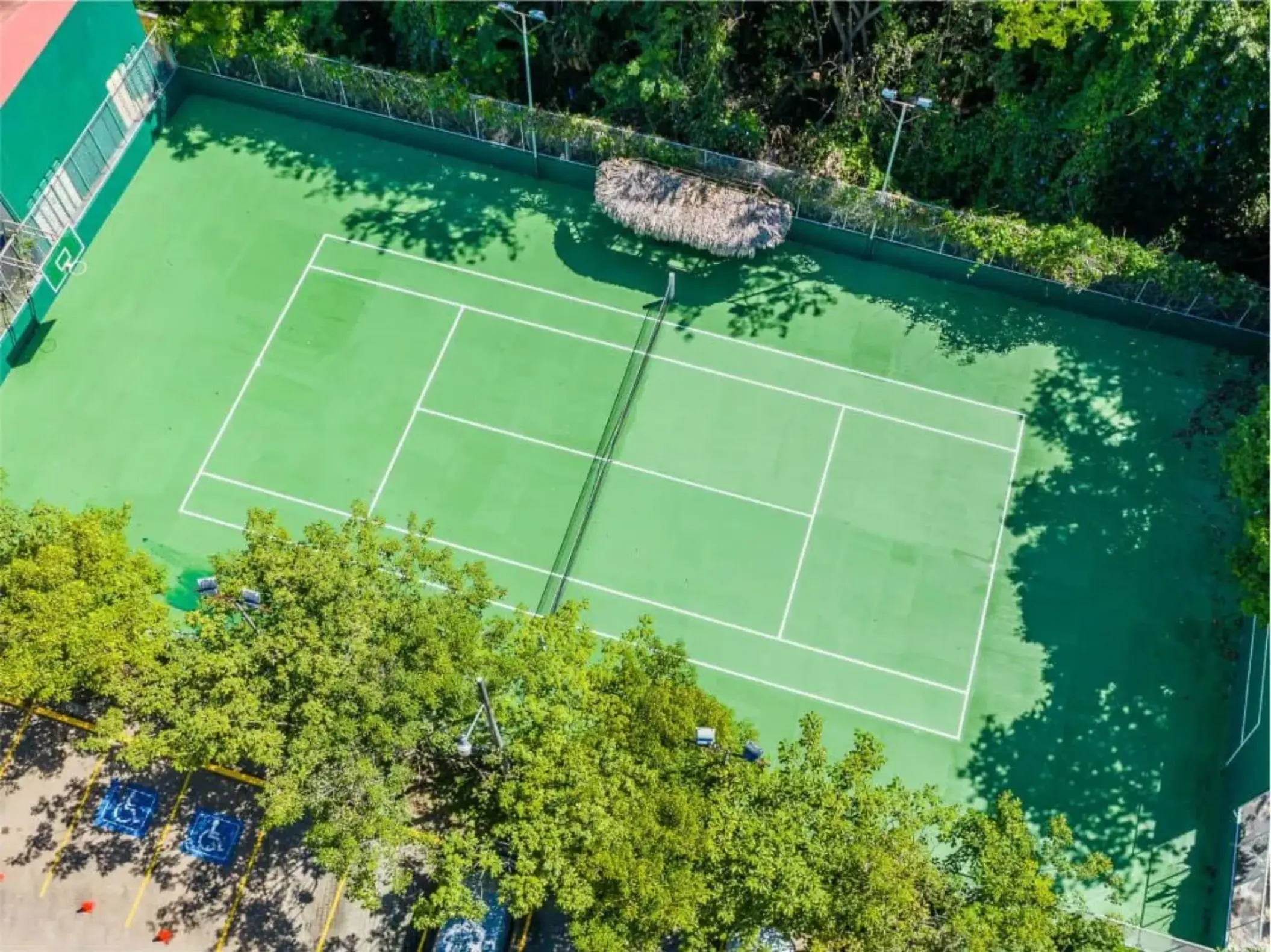 Aerial view of a tennis court surrounded by lush trees at Margaritaville Playa Flamingo, Liberia