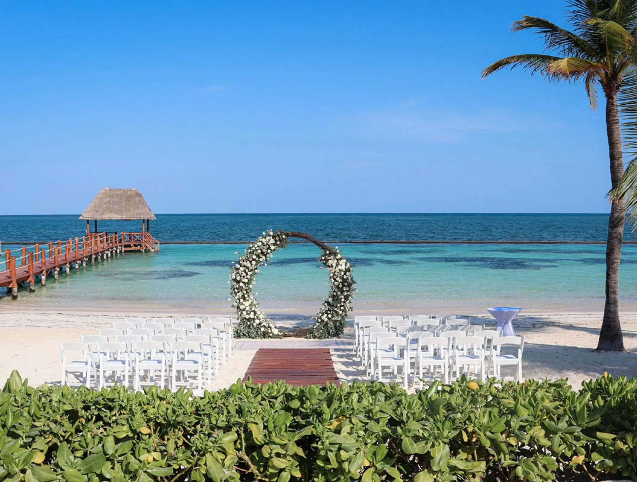 Beachfront wedding ceremony with white floral arch at Margaritaville Island Reserve Riviera Cancun, Cancun