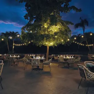 Outdoor restaurant terrace at night with string lights and woven chairs at Armony Marival, Puerto Vallarta