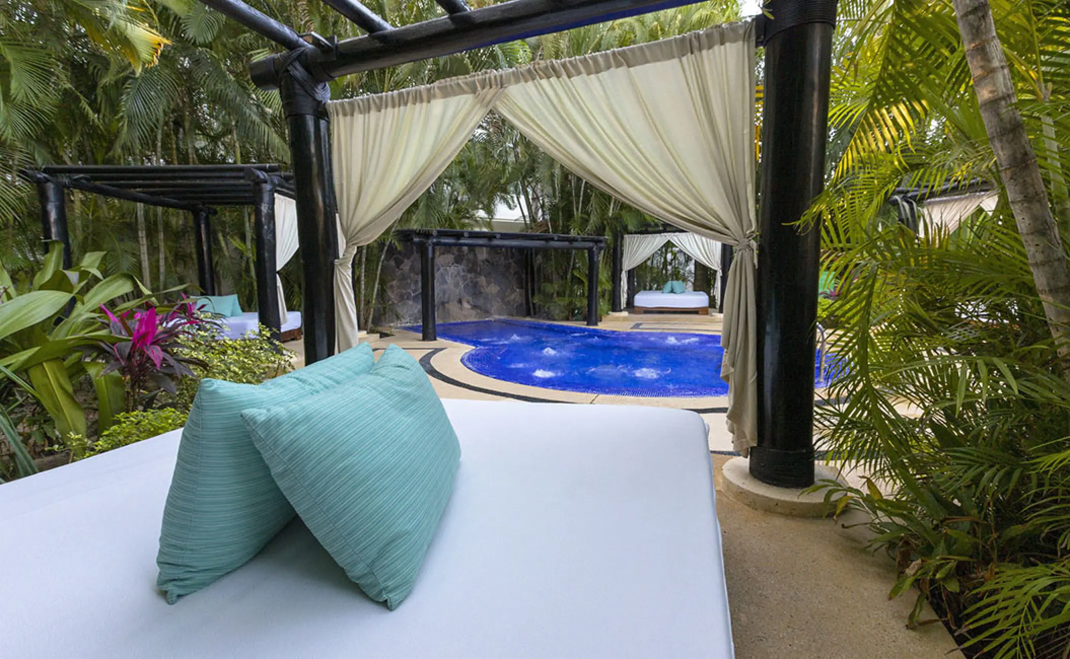 Private Bali beds surrounding an outdoor hot tub at Marival Distinct, Puerto Vallarta