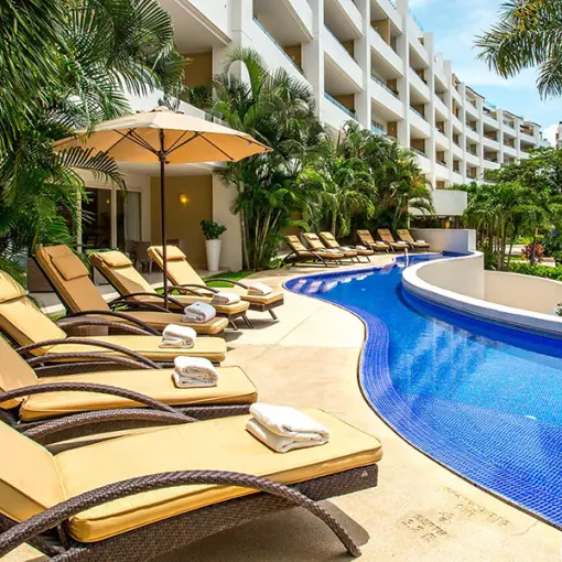 Marival Distinct Residences poolside lounge chairs by a winding blue pool, Puerto Vallarta