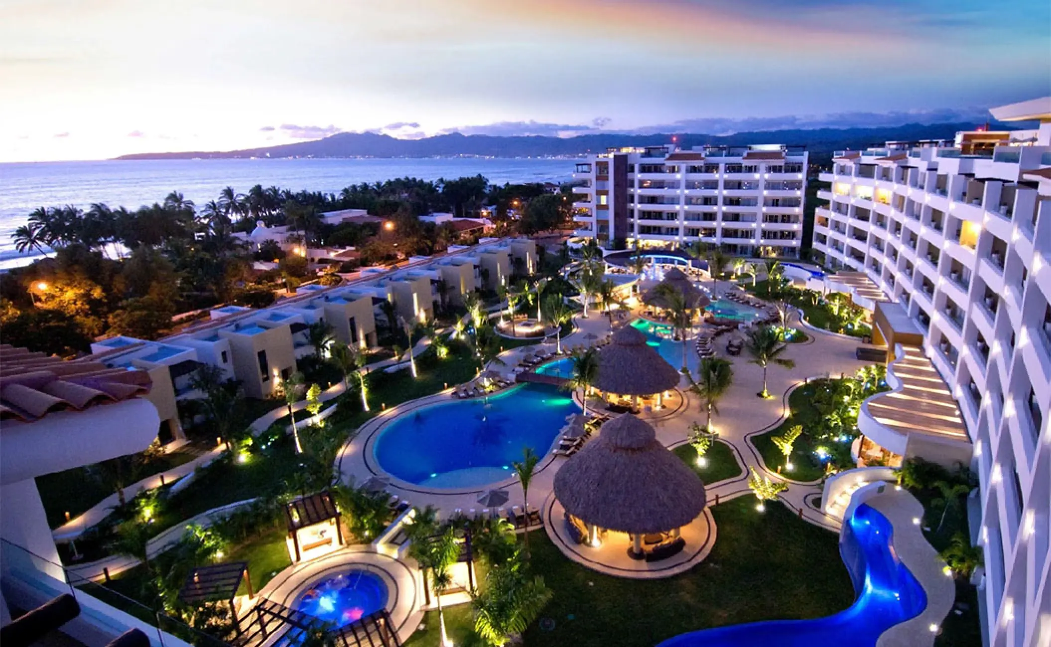 Night view of lit pools and villas at Marival Distinct Luxury Residences, Puerto Vallarta