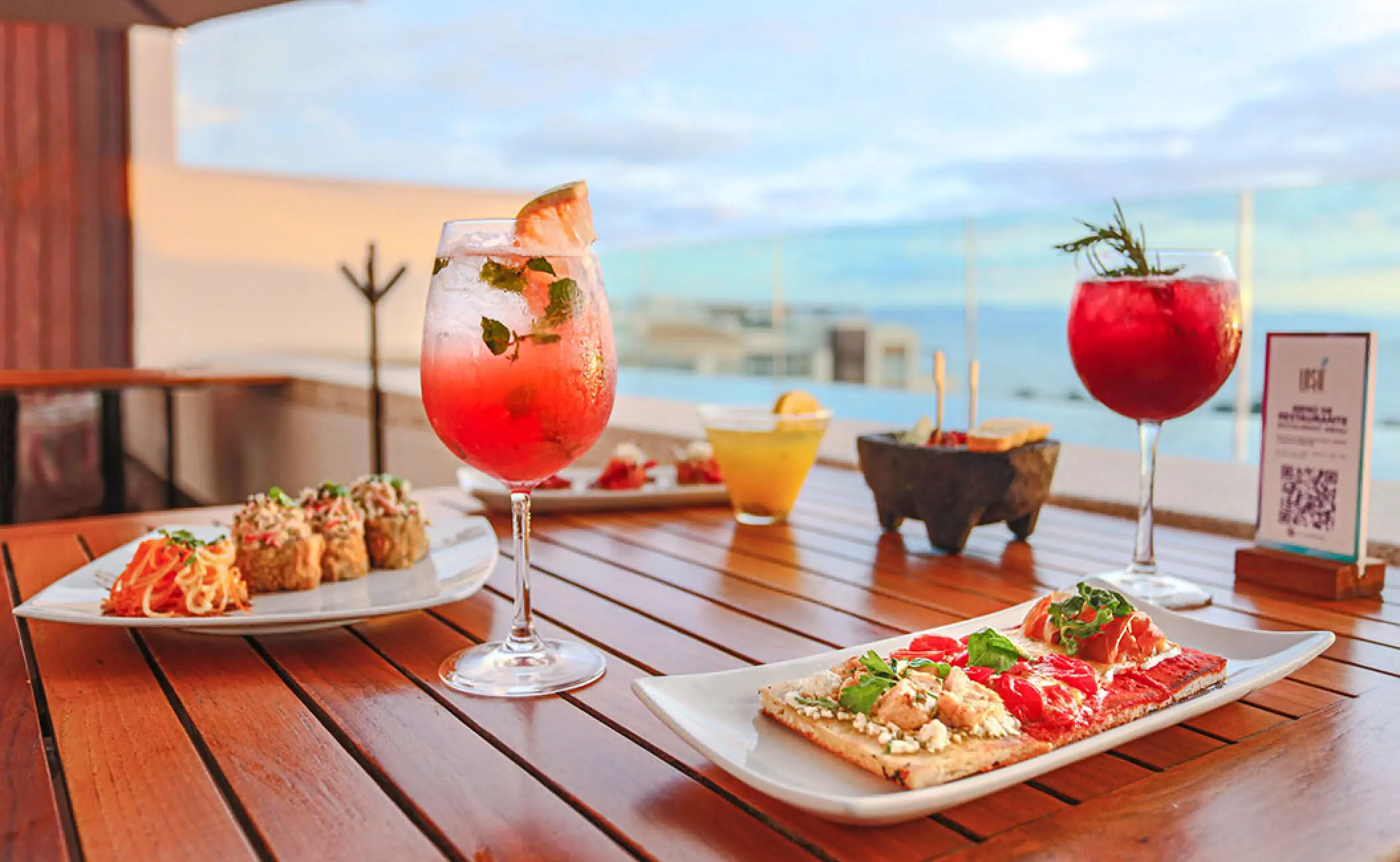 Cocktails and appetizers on a wooden table at Marival Distinct, Puerto Vallarta