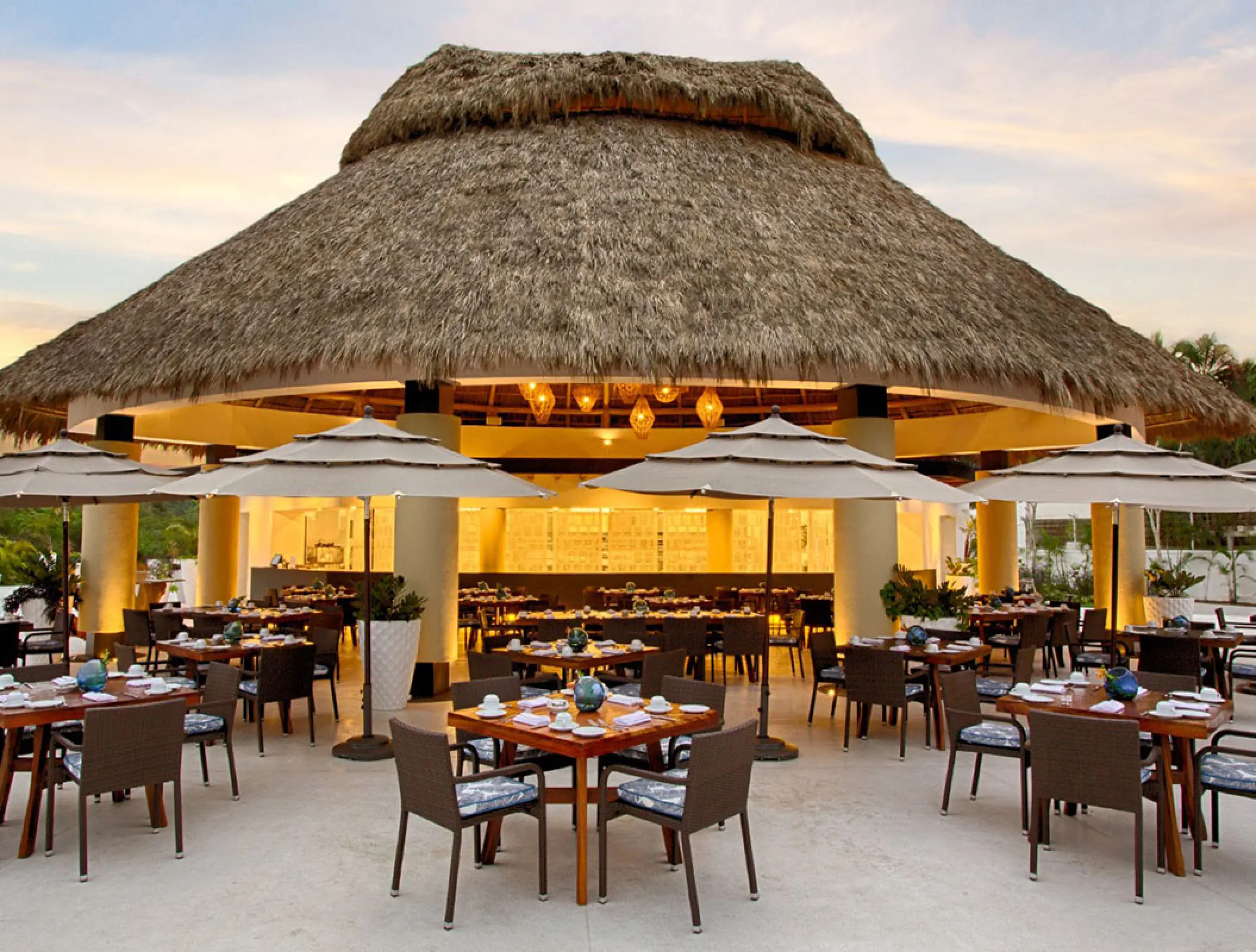 Mozzamare Beach Club outdoor dining area under a large palapa at Marival Distinct, Puerto Vallarta