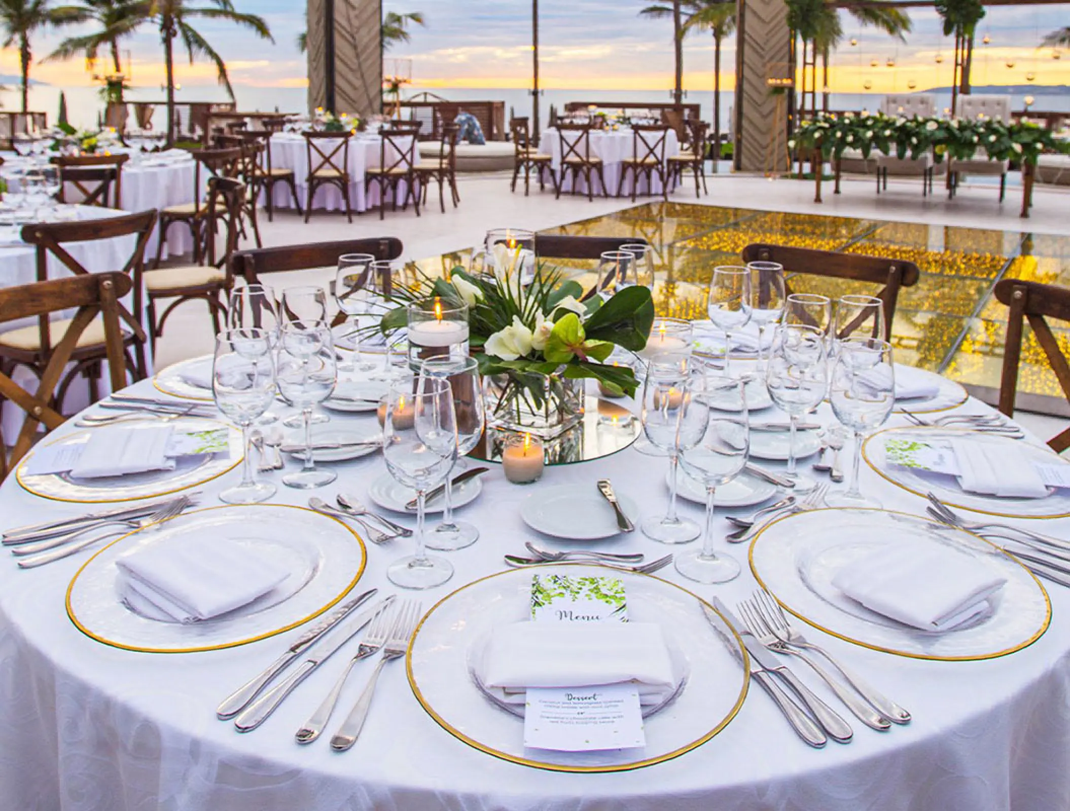 Wedding reception table setting with floral centerpiece and gold-rimmed plates at Marival Distinct, Puerto Vallarta