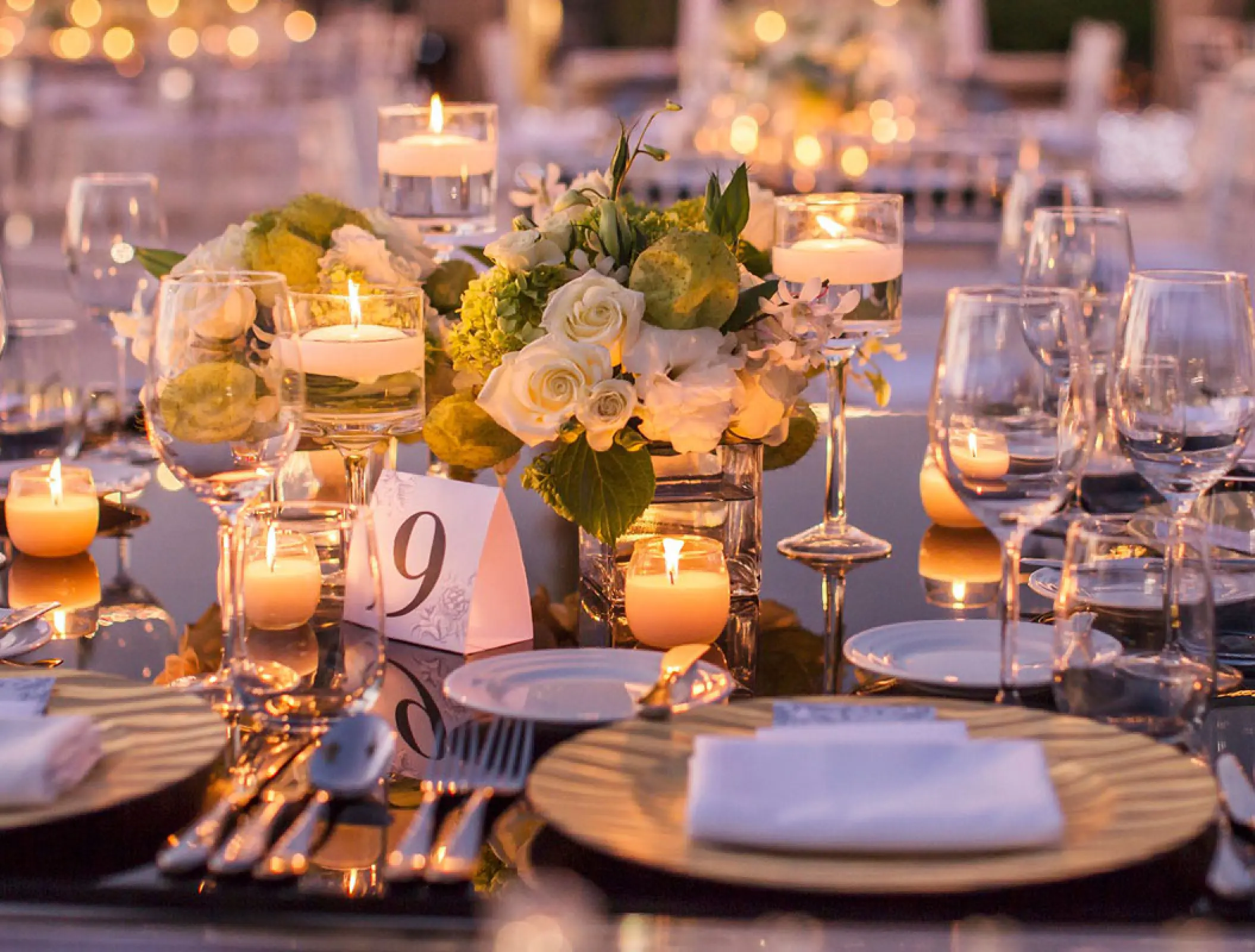 Wedding reception table setting with glowing candles and white roses at Marival Distinct, Puerto Vallarta