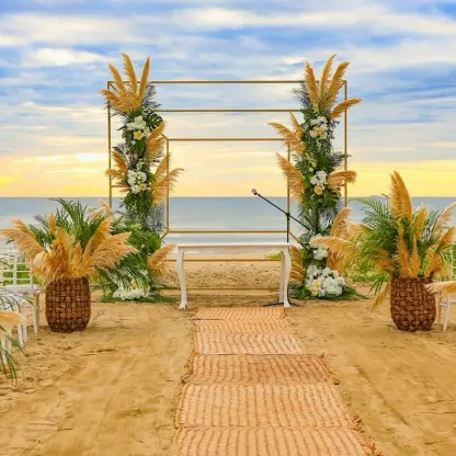 Beach wedding ceremony with a gold arch and pampas grass at Marival Distinct, Puerto Vallarta